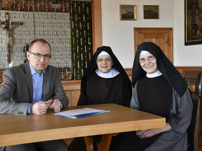Kanzler Dr. Claudius Luterbacher sitzt mit zwei Nonnen vom Kloster St. Scholastika am Tisch
